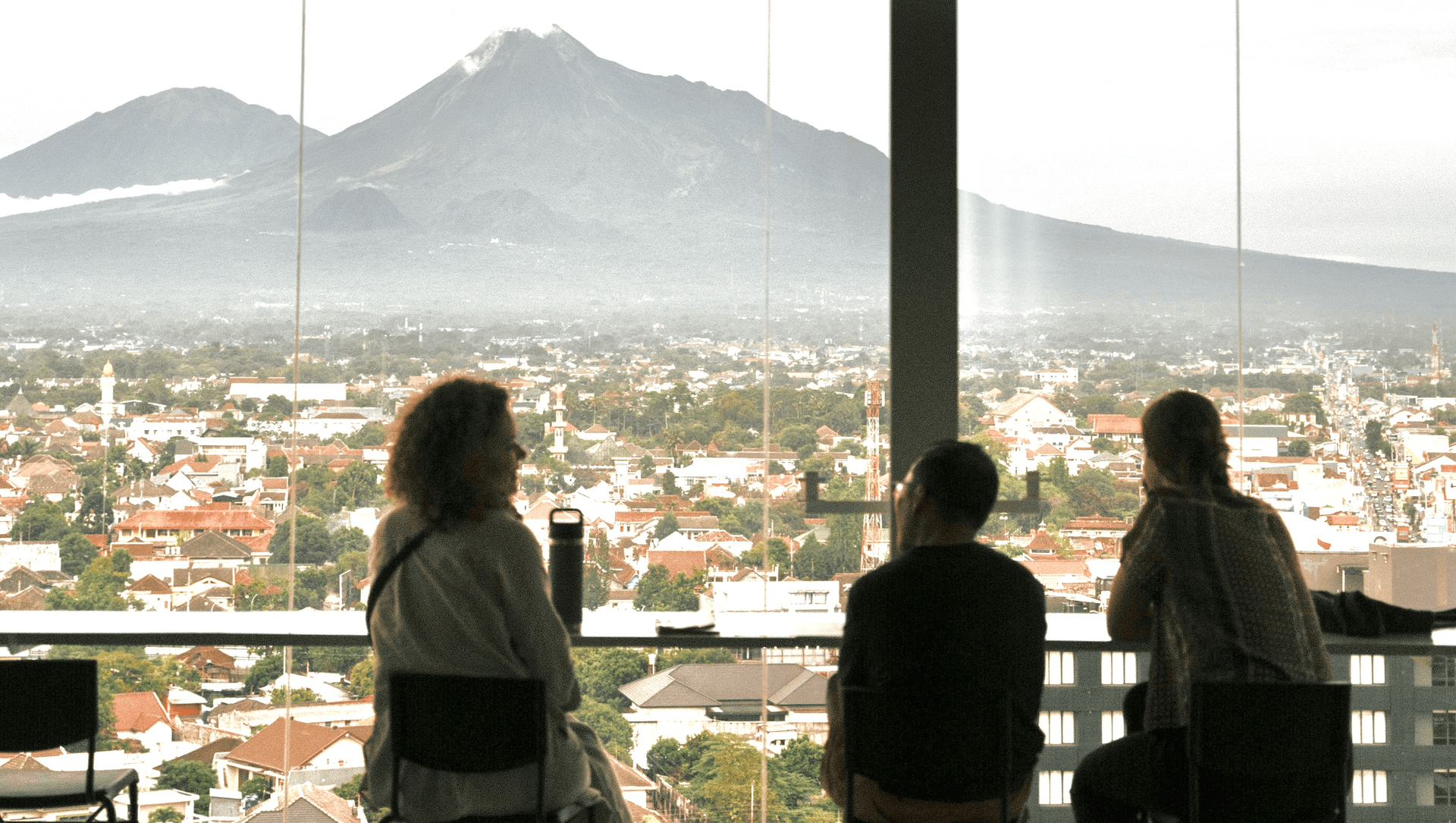Three guests looking out over Jogja rooftops toward Merapi at Alfresco Dining