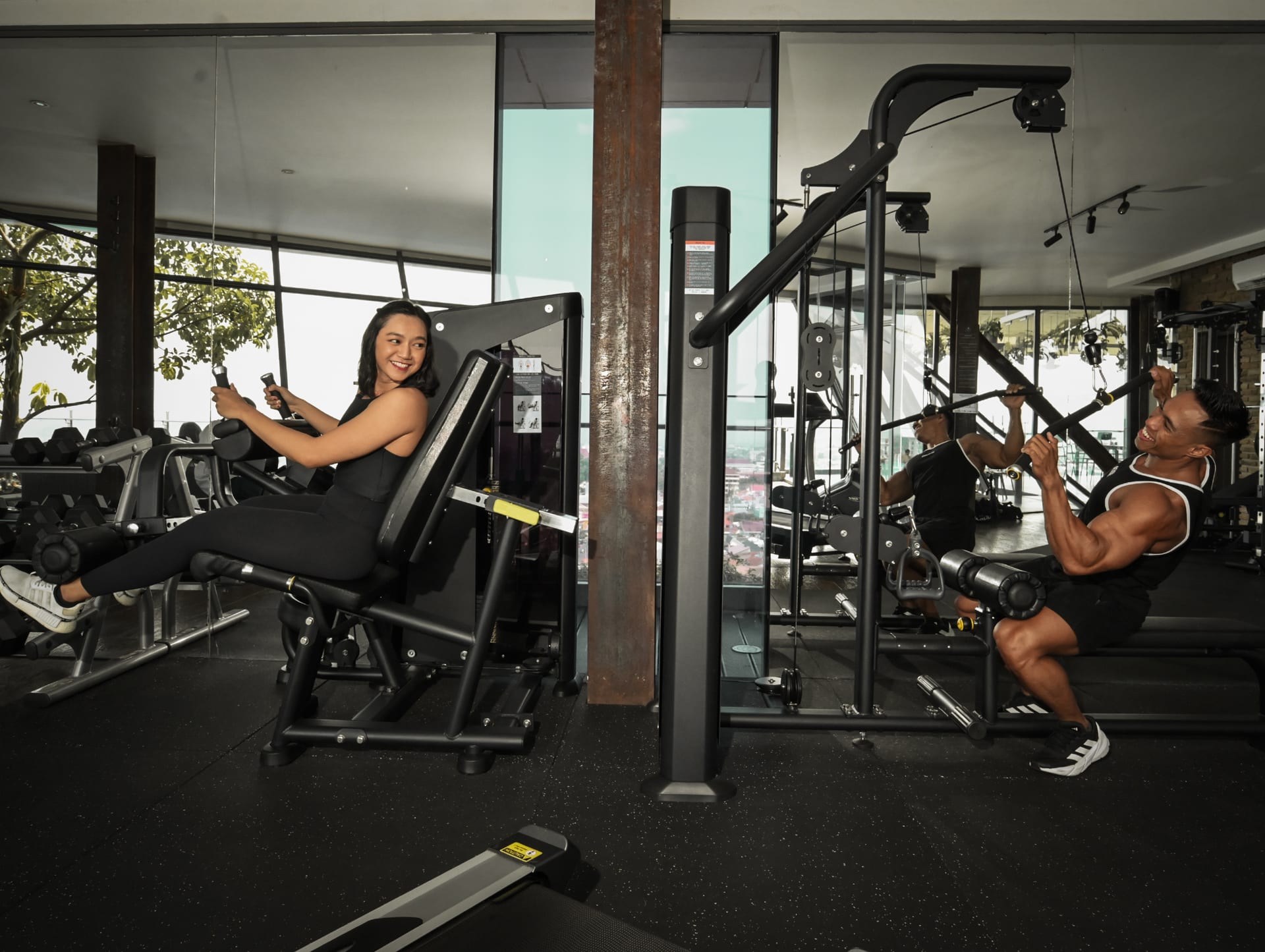Guests training on cable machines in the glass-walled gym above the Jogja skyline