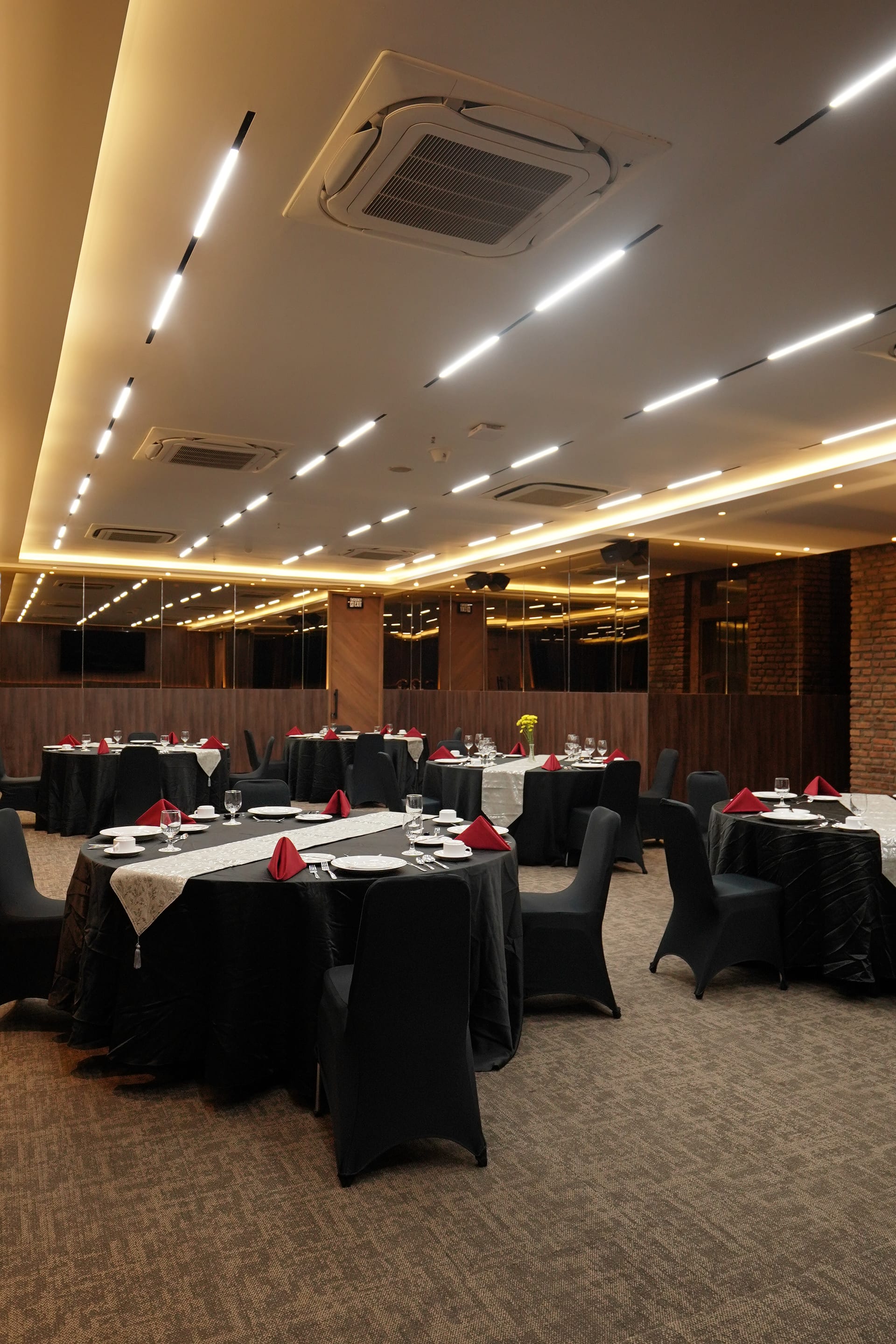 Round dinner tables dressed in black with red napkins under mirrored walls in the Omong-Omong meeting room