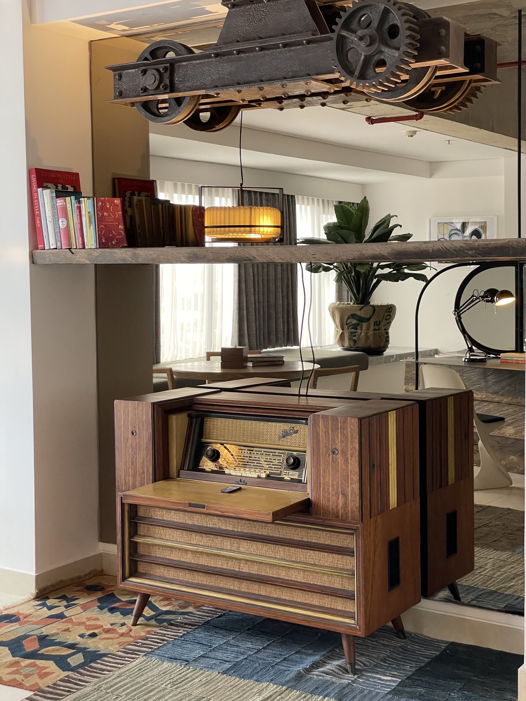 Vintage radiogram console under an industrial gear sculpture in the PULANG ke UTTARA lobby